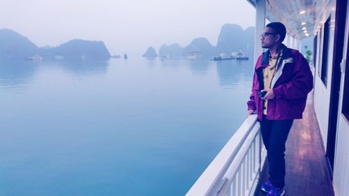 Man looking away while standing on corridor of ferry at ha long bay