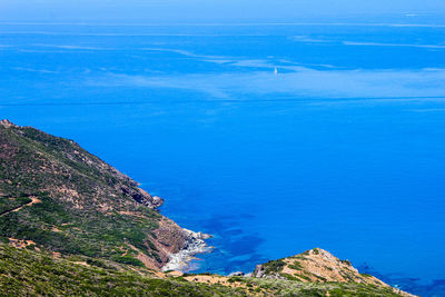 High angle view of sea and mountains against blue sky