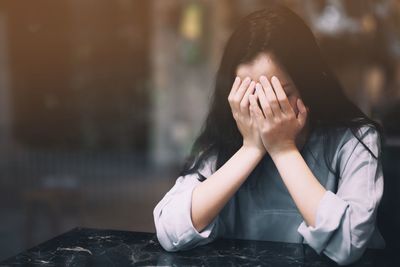 Portrait of woman covering face outdoors