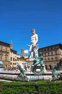 Low angle view of statue against building against clear blue sky