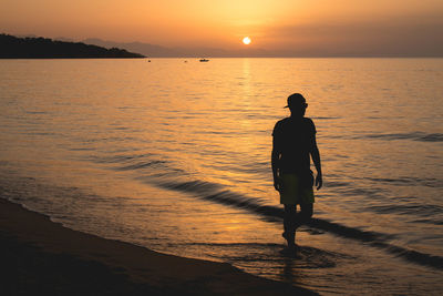 Man walking on beach during sunset