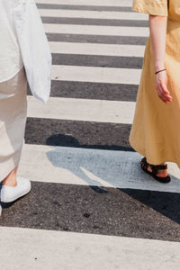 Low section of man and woman walking on crosswalk