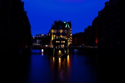 Illuminated buildings by river at night