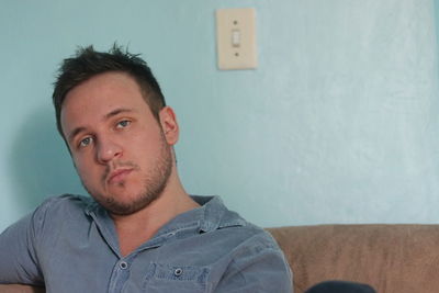 Portrait of young man against wall at home