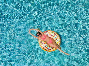 Directly above shot of woman on pool raft floating in swimming pool