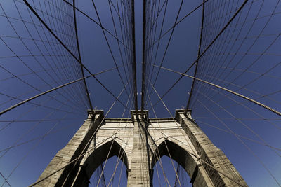 Low angle view of brooklyn bridge against blue sky on sunny day