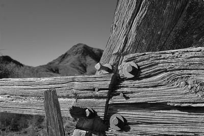 Close-up of wooden post against mountain and sky