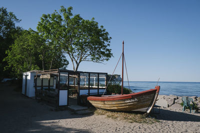 Sailboats moored on beach against clear blue sky