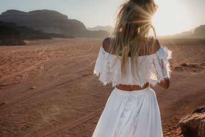 Woman in dress standing on landscape against sky