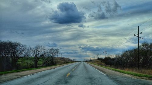 Empty country road against cloudy sky