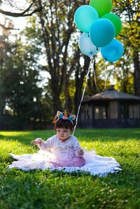 Cute girl with balloons sitting in park
