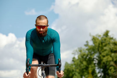 Low angle view of man riding bicycle against sky