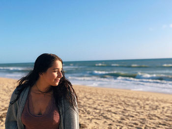 Beautiful young woman on beach against sky