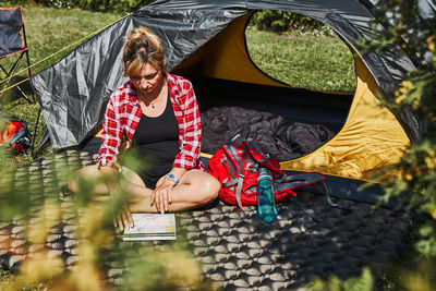 Woman planning next trip while sitting with map in tent. spending vacations outdoors. camp life