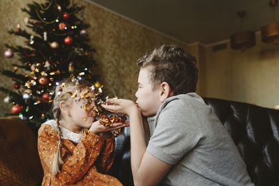 Playful siblings blowing confetti at home