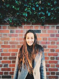 Young woman standing on brick wall