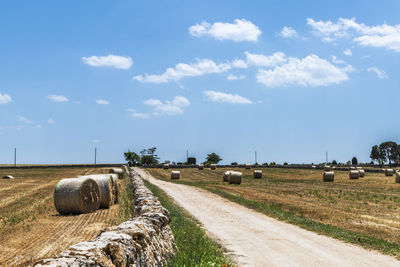 Hay bales on field against sky