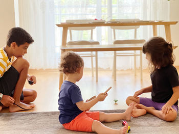 Rear view of friends sitting on mobile phone