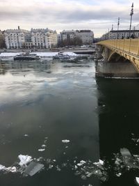 River by cityscape against sky