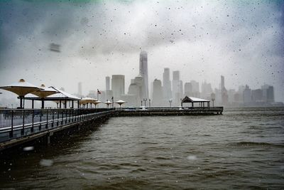 Pier over river against buildings against sky