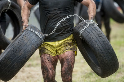 Midsection of man holding tire while exercising outdoors