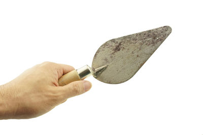 Cropped hand of man holding trowel over white background