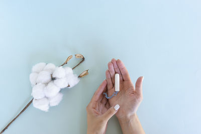 Woman hand holds a sanitary tampon with the cotton lying next to it