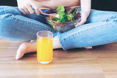 Midsection of woman holding drink on table