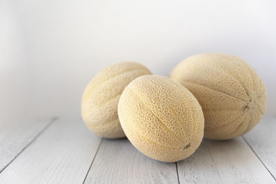 Three fresh cantaloupes laying on white boards