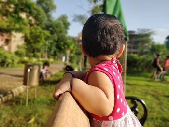 Close-up of cute baby girl looking away on bench in park