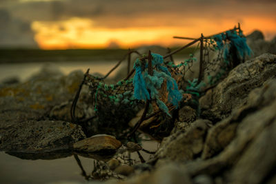 Close-up of fishing net against sky during sunset