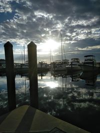 Sailboats moored at harbor against sky during sunset