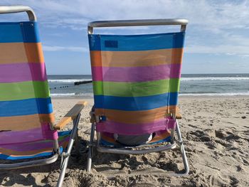 Multi colored chairs on beach against sky