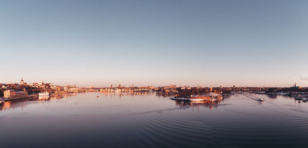 Boats moored in river against clear sky at sunset