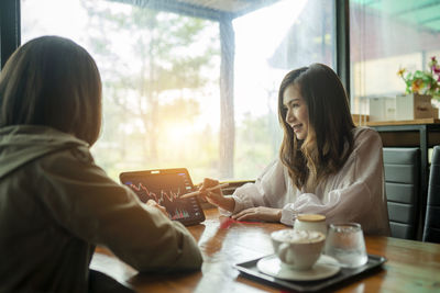 Young woman using mobile phone while sitting at restaurant