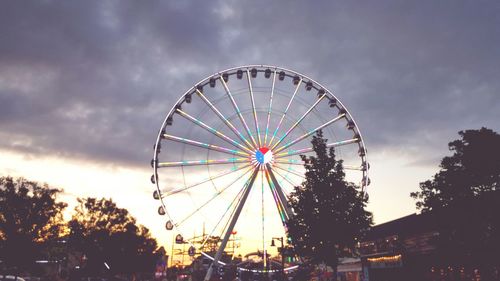 Low angle view of ferris wheel against cloudy sky
