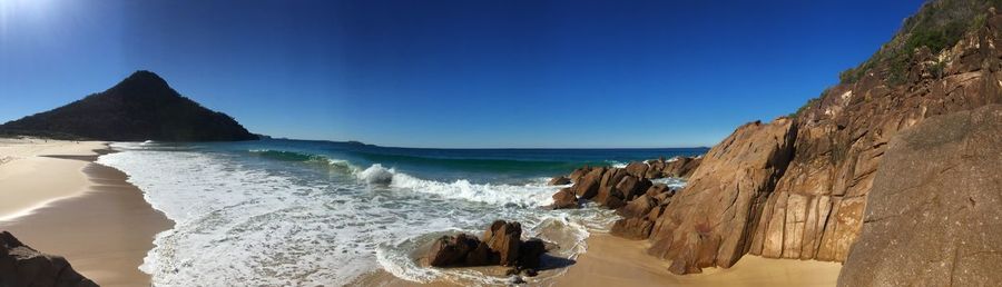 Panoramic view of beach against clear blue sky