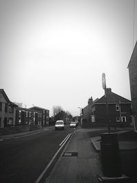 Cars on road against clear sky in city