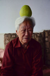 Portrait of senior woman with pummelo on head