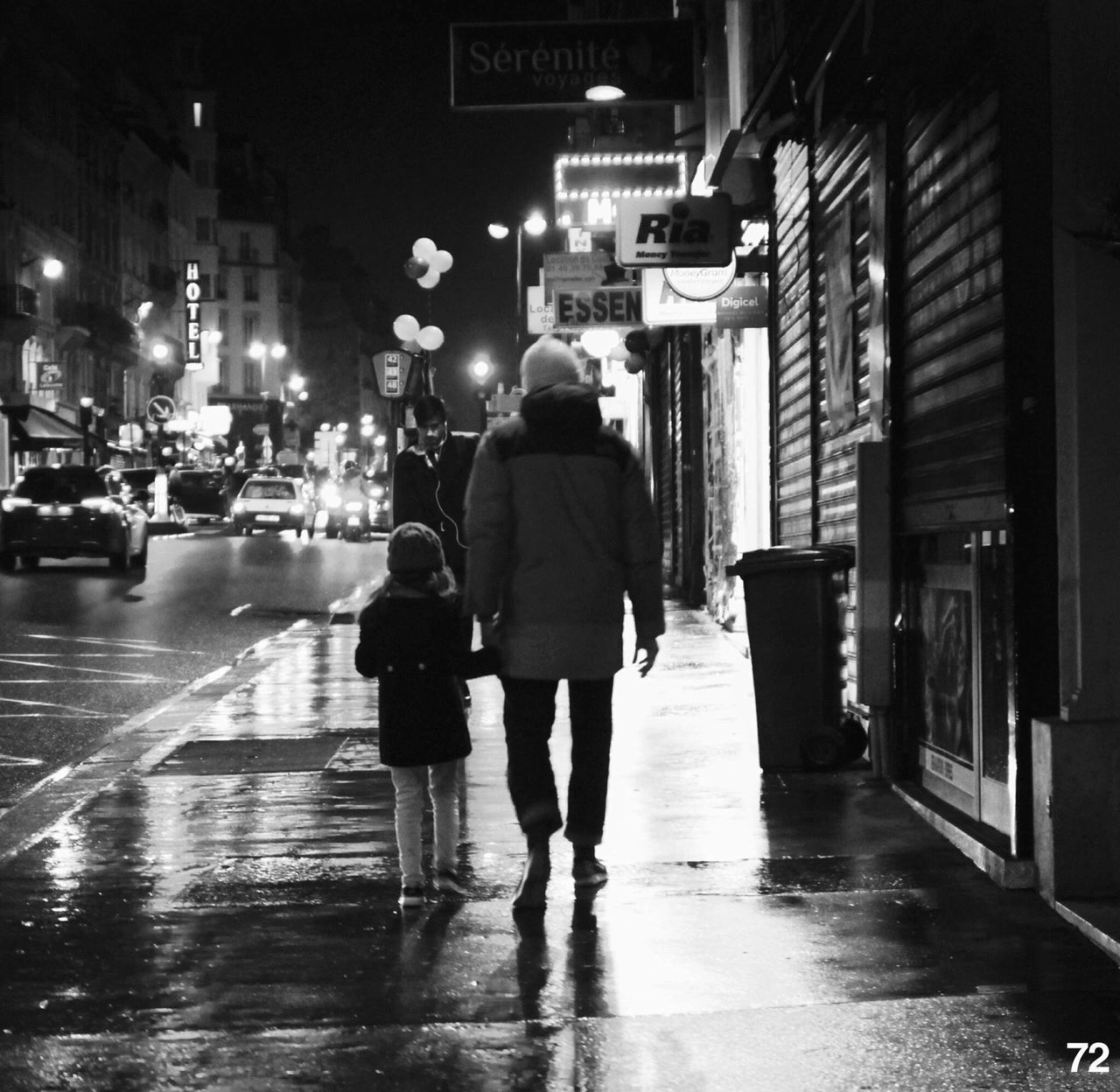 REAR VIEW OF WOMAN WALKING ON WET STREET AT NIGHT