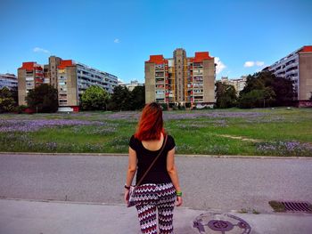 Rear view of woman standing by buildings in city