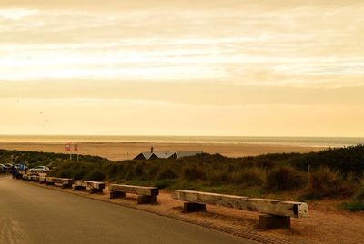 Road by sea against sky during sunset