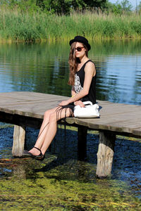 Young woman sitting on wood against lake