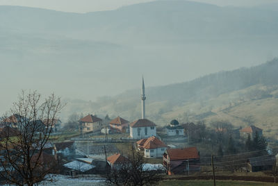 Houses and trees against sky during foggy weather