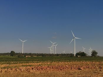 Windmills on field against clear sky