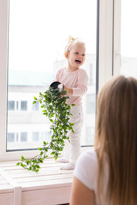 Side view of girl playing with christmas tree at home