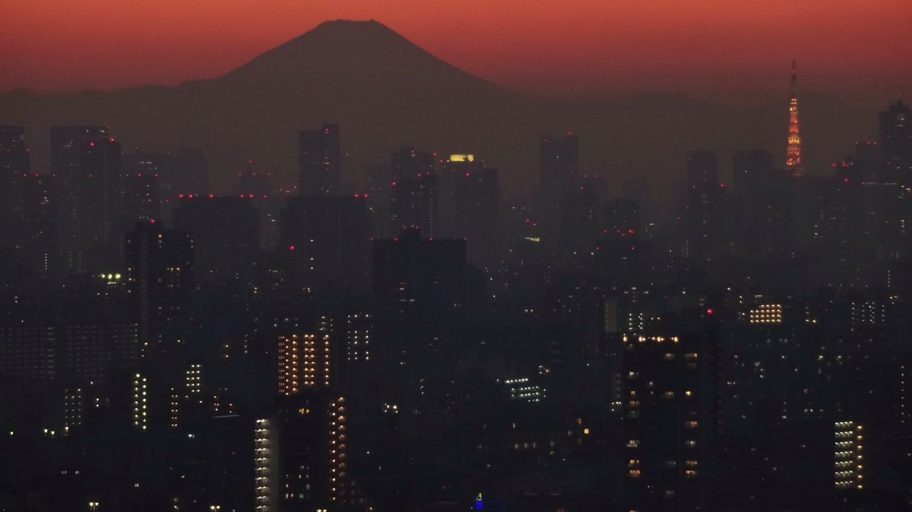 building exterior, city, cityscape, architecture, built structure, skyscraper, sunset, tower, tall - high, crowded, illuminated, modern, sky, orange color, high angle view, urban skyline, capital cities, office building, mountain, travel destinations