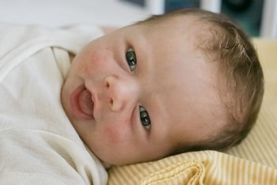 Close-up portrait of cute baby lying on bed