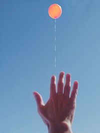 Low angle view of hand against blue sky