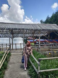Full length of woman with arms raised against sky